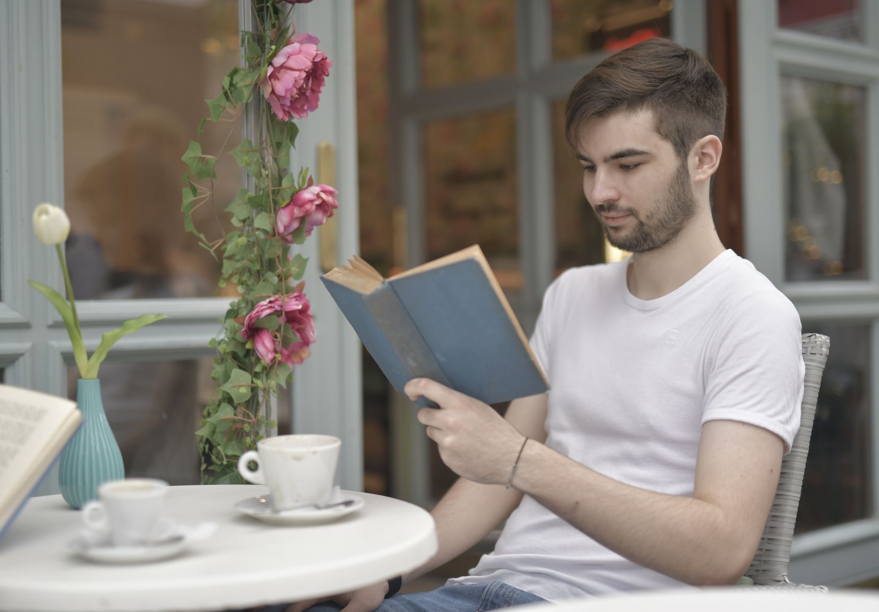 カフェのテラス席で本を読む男性