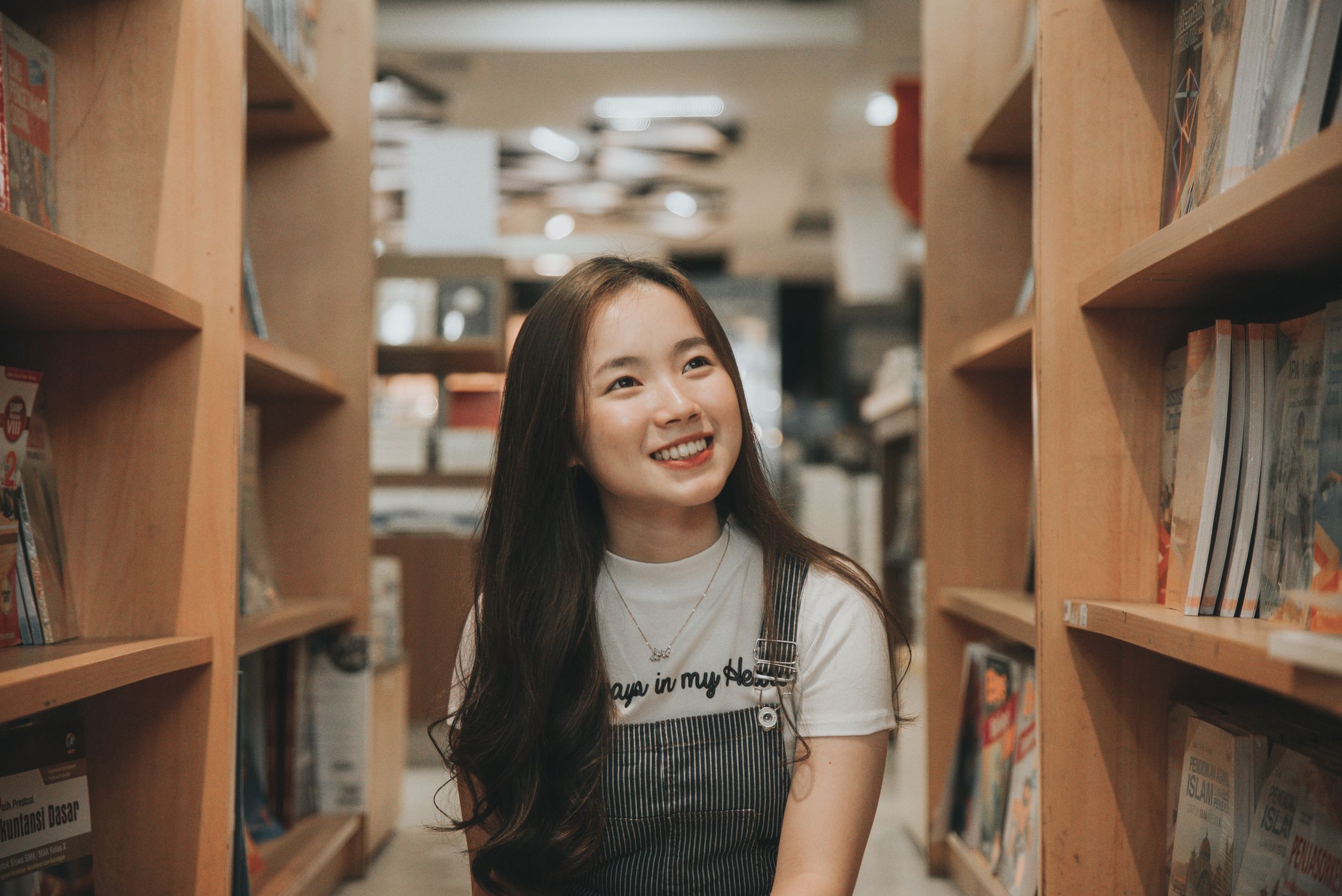 書店の通路で楽しそうに本を眺める女性
