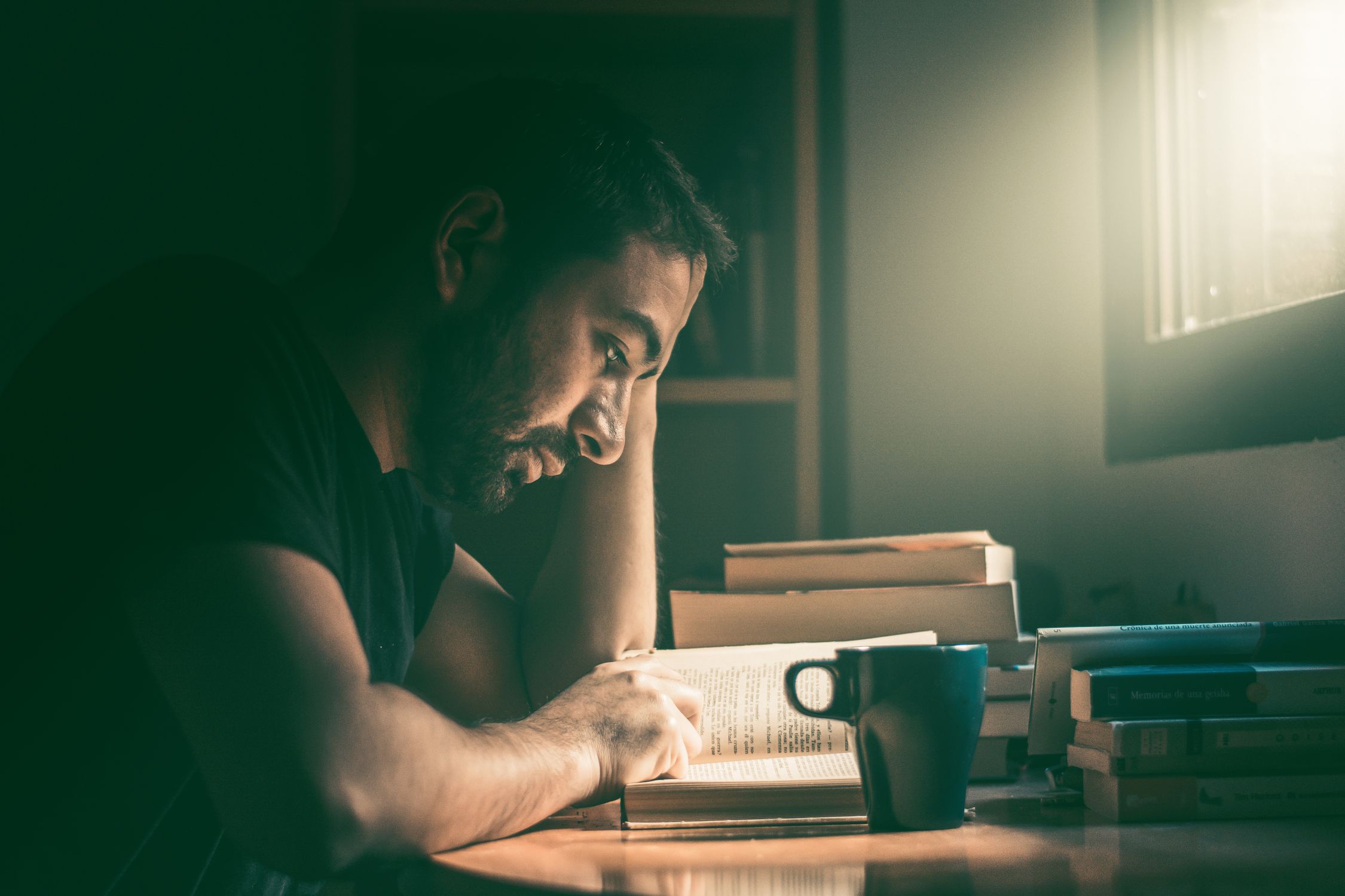 コーヒーを片手に本を読みふける様子