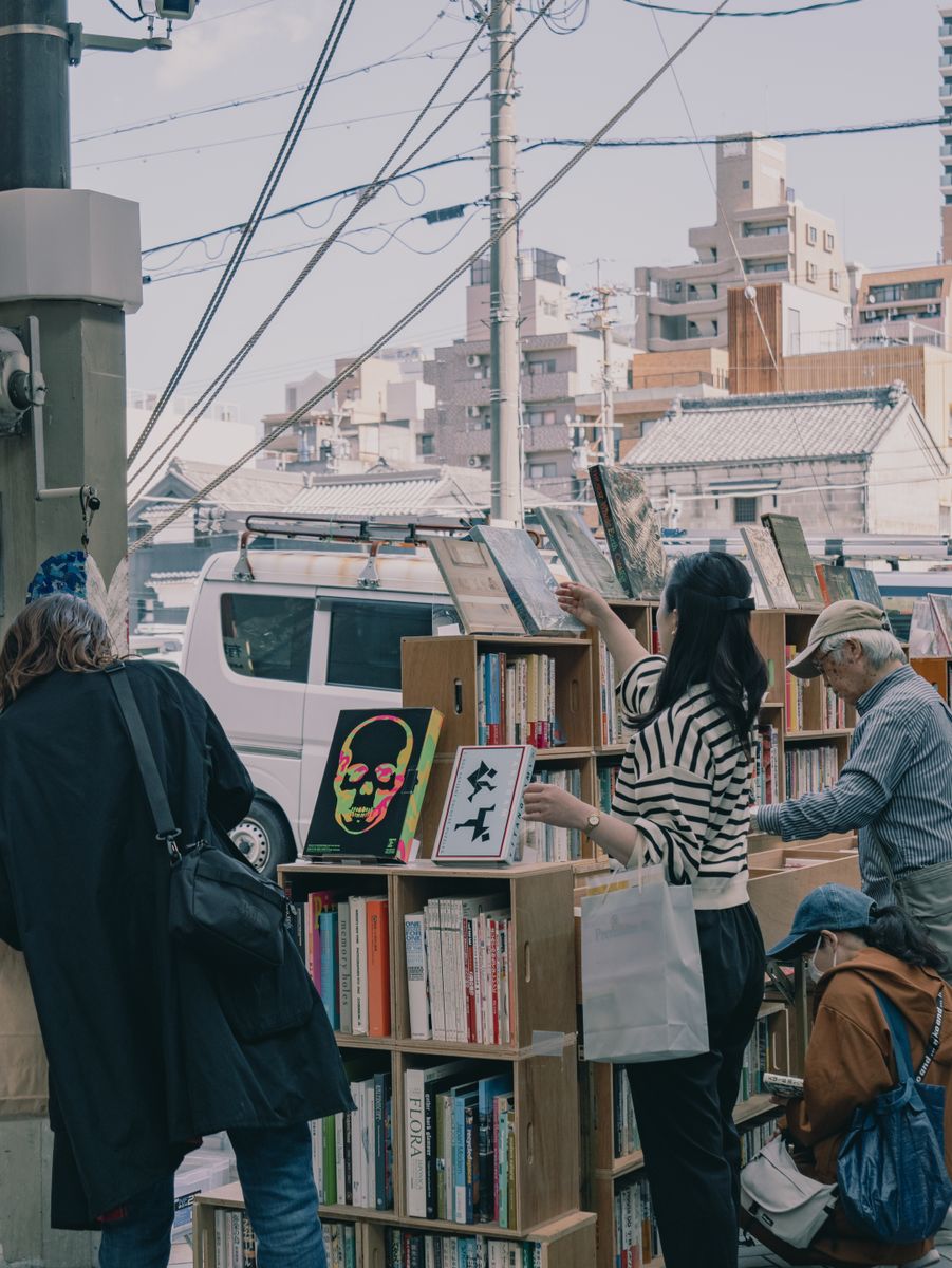 屋外の古書市で本を選ぶ人々