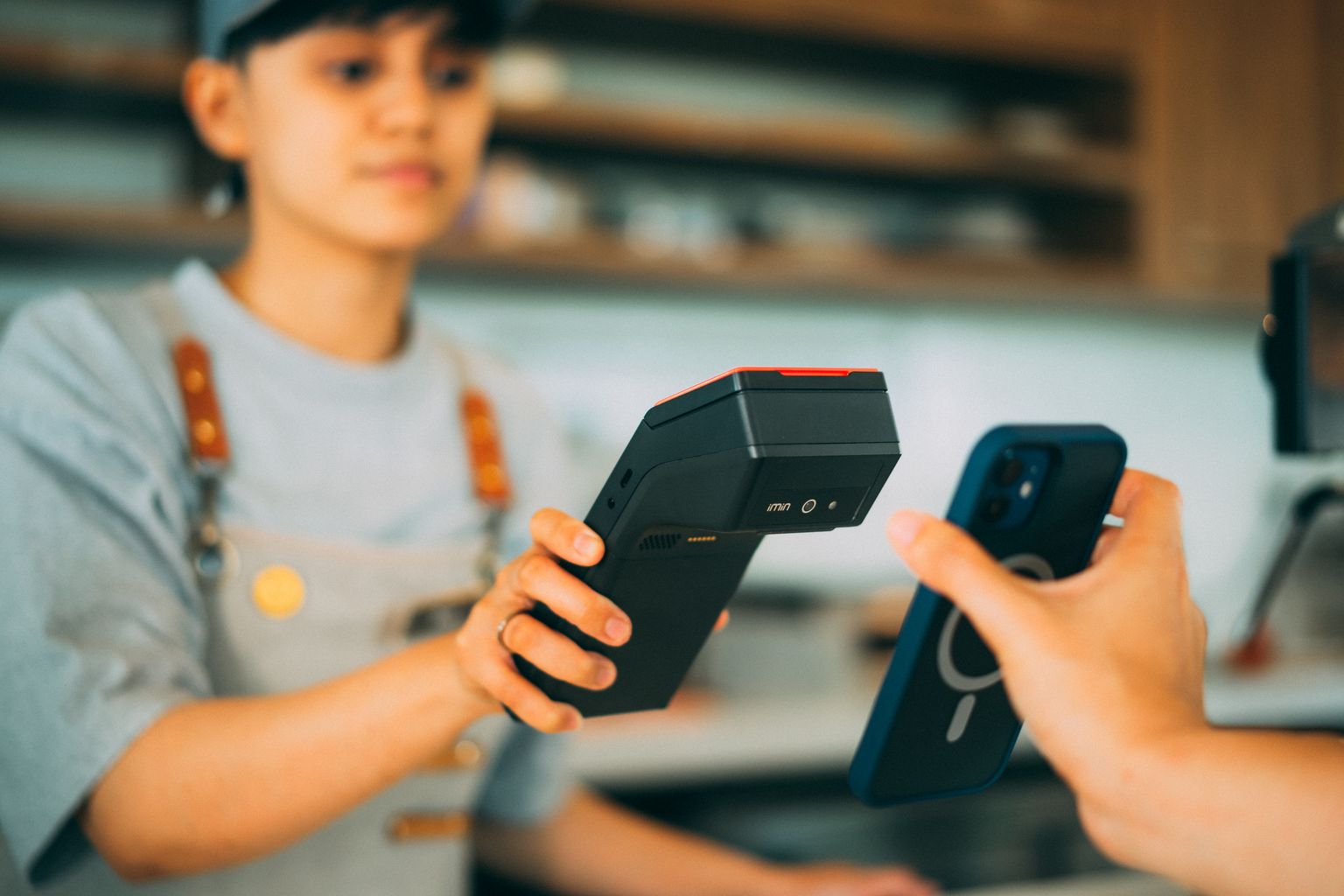 コンビニのレジでタッチ決済端末にスマートフォンをかざす様子