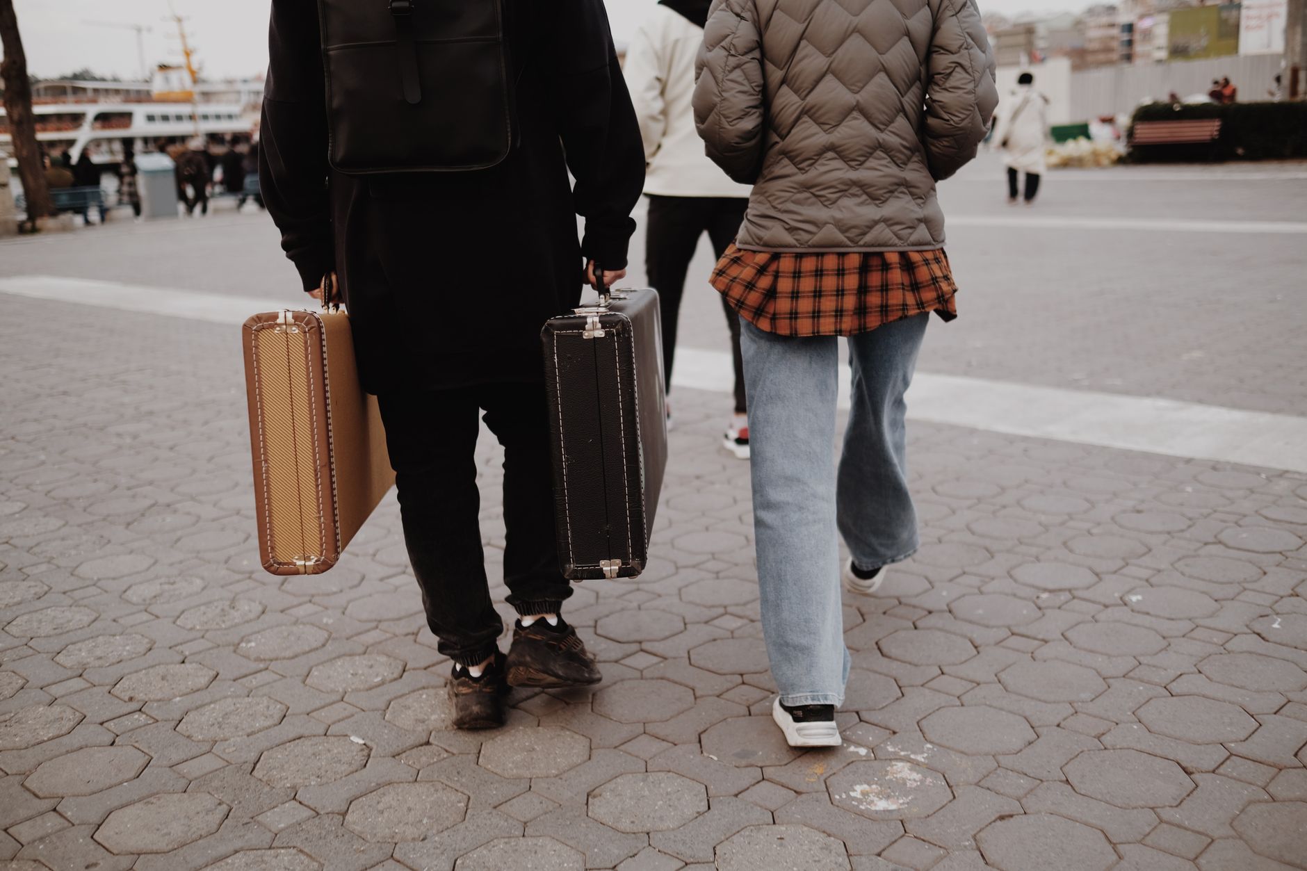 Two travelers walking in city carrying vintage suitcases, reflecting urban travel lifestyle.