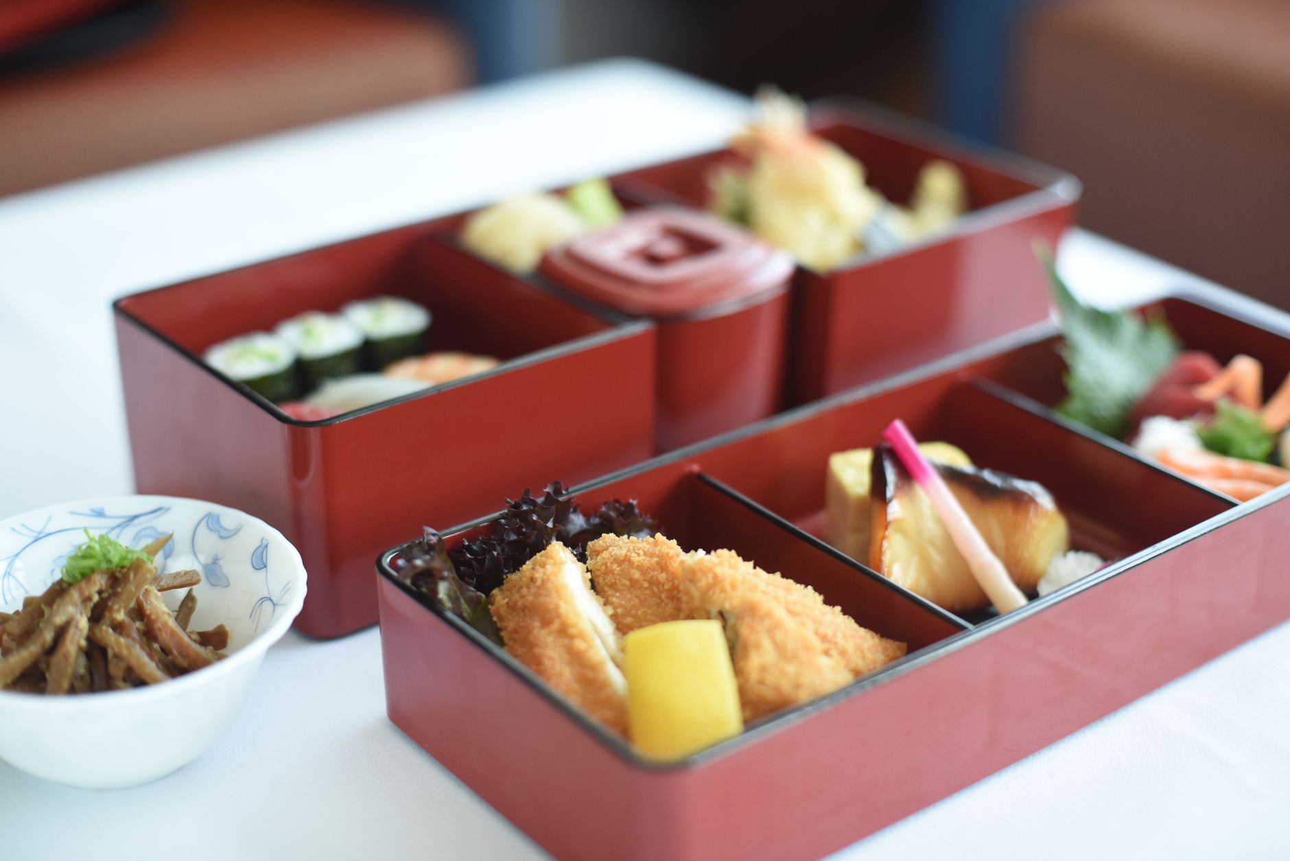 High-quality image of a traditional Japanese bento box with sushi, tempura, and garnishes.