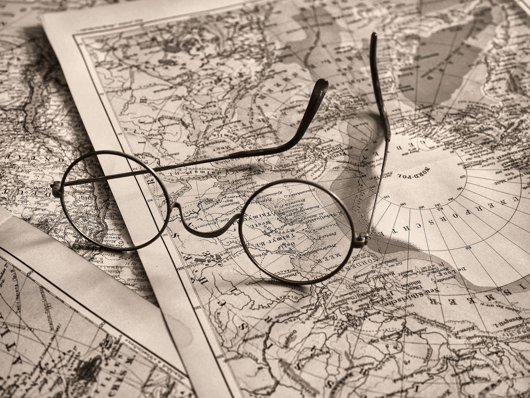 Round eyeglasses rest on an antique world map, evoking a sense of exploration.