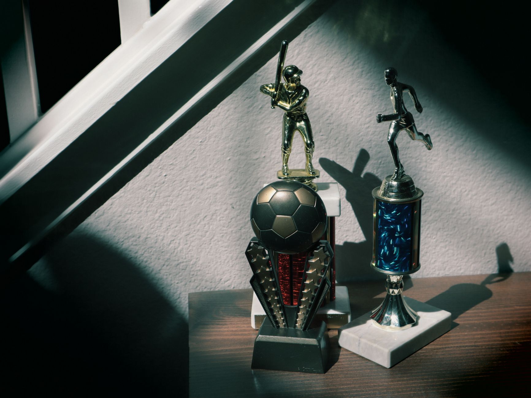 A collection of soccer and baseball trophies displayed indoors, capturing childhood nostalgia.