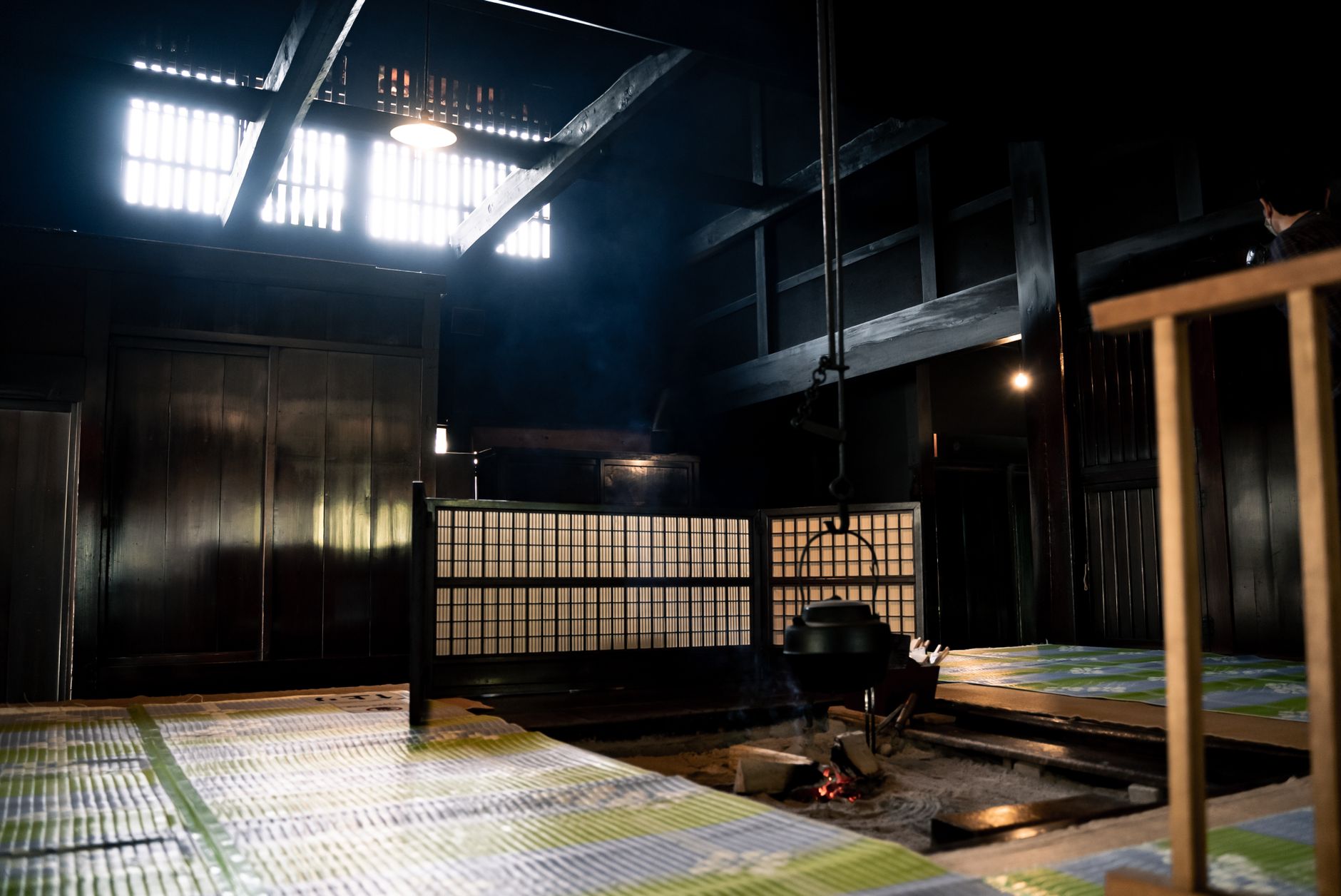 A cozy traditional Japanese ryokan interior with a hanging cauldron over an open hearth, reflecting cultural heritage.
