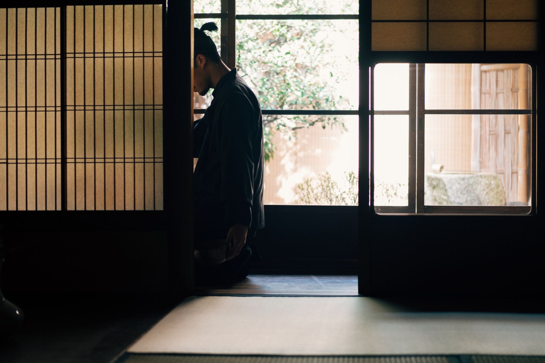 A person meditates in a tranquil Japanese room with soft light filtering through shoji screens.