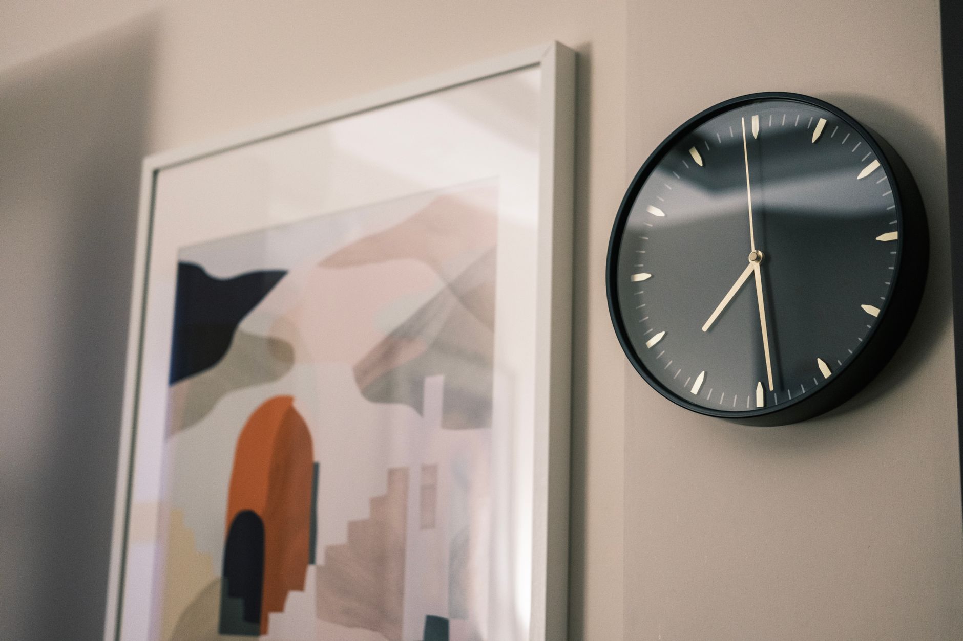 A minimalist wall clock and abstract painting in a modern interior setting.