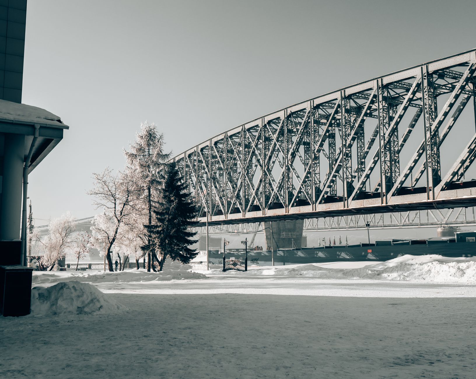 A snowy urban landscape featuring a railway bridge in Novosibirsk, Russia.